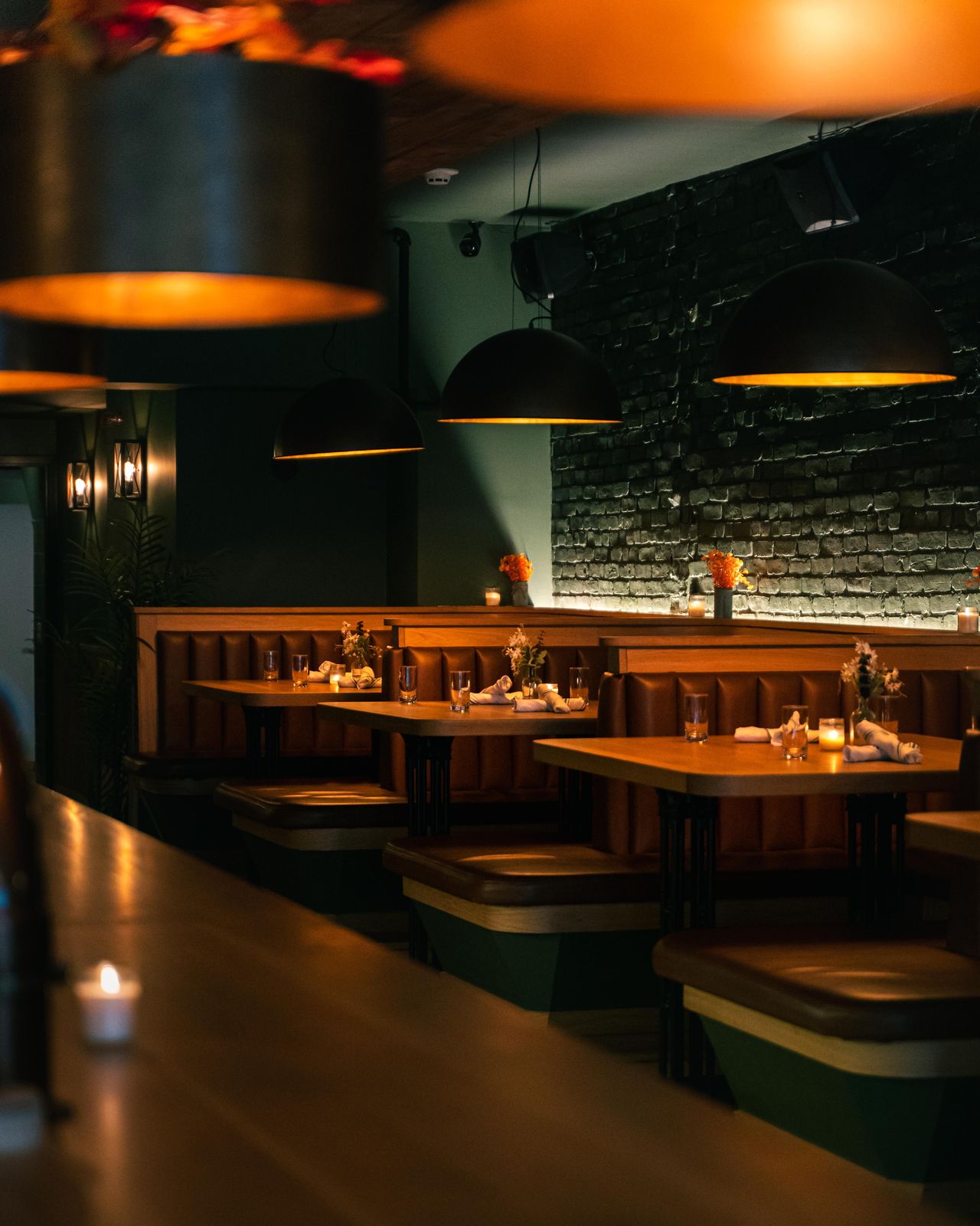 Dear Maud's dining room set for service, with warm pendant lighting over the booths