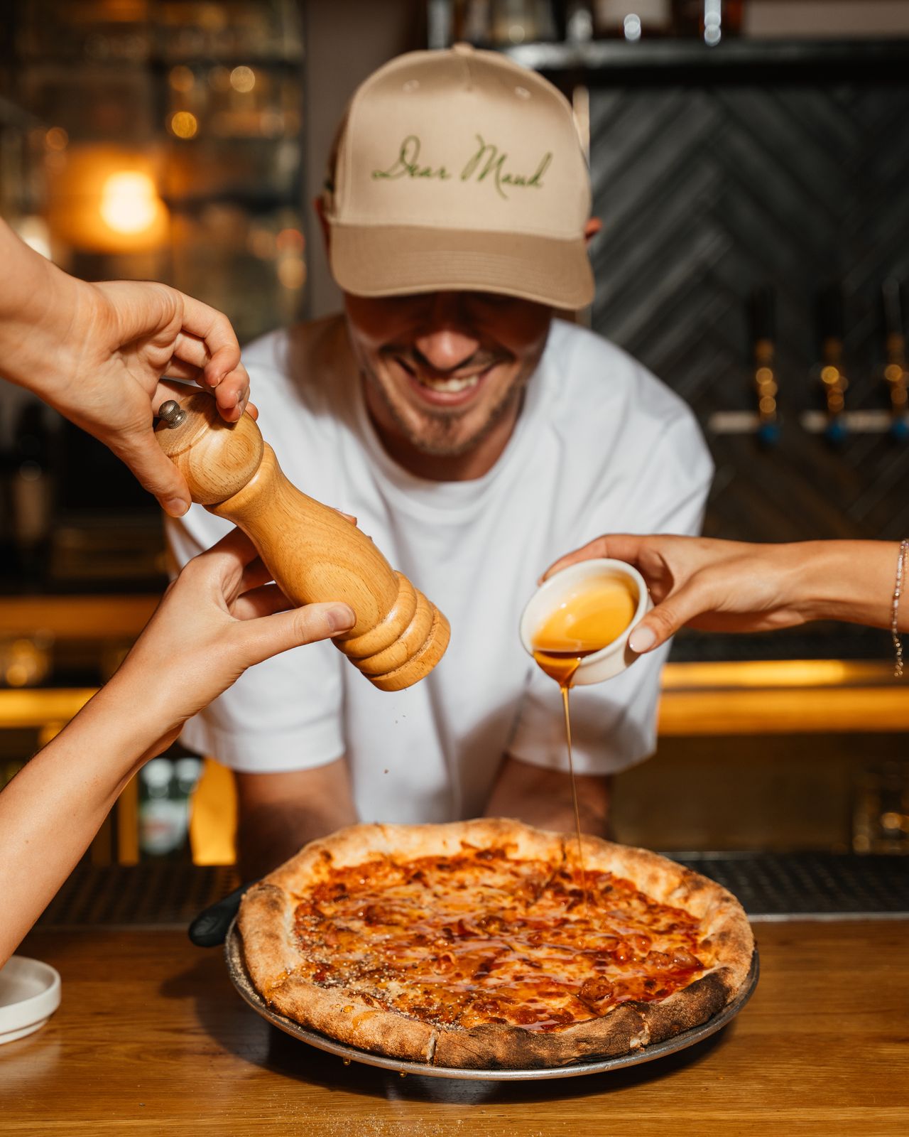A bartender finishing a Fresh Tomato Mozzarella pizza at the Dear Maud bar during happy hour