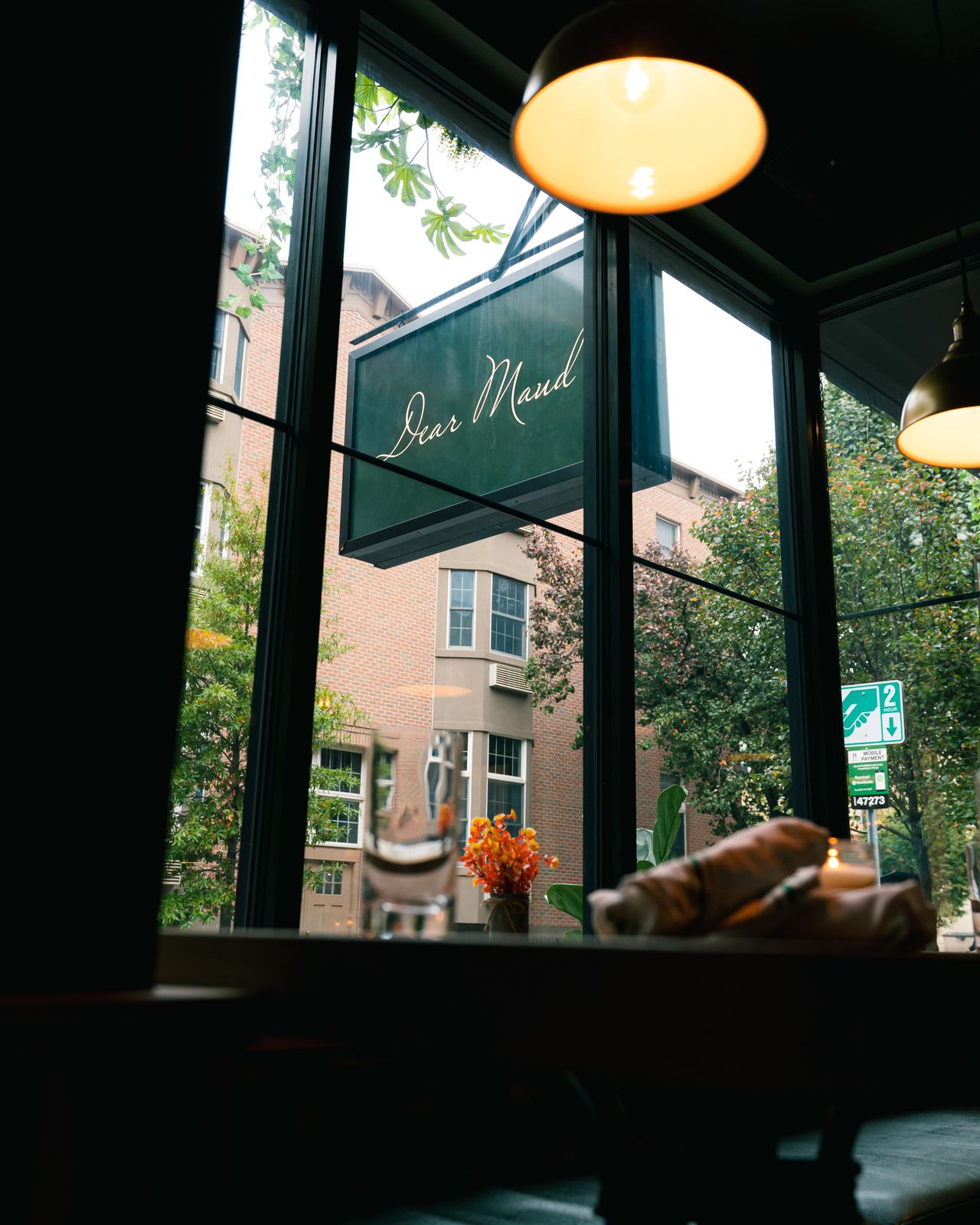 A table set by Dear Maud's front window, looking out at the illuminated storefront sign